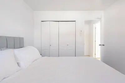 a white bedroom with a large white bed at Verone 4 Appartement 4,5 Meublé 2ch Laval, Canada in Laval