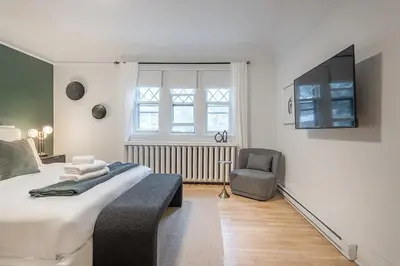 a bedroom with a bed and a chair and a television at 4BR Penthouse - Parking - 2 King & 2 Queen in Montréal