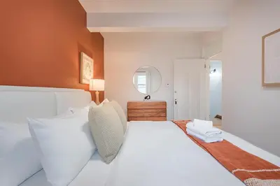 a bedroom with a white bed and a mirror at 4BR Penthouse - Parking - 2 King & 2 Queen in Montréal