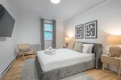 a bedroom with a large white bed and a chair at 4BR Penthouse - Parking - 2 King & 2 Queen in Montréal