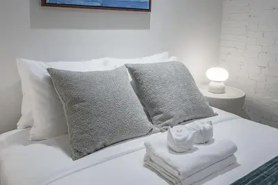 a white bed with pillows and towels on it at Bright & Modern 2BR - Golden Square Mile in Montréal