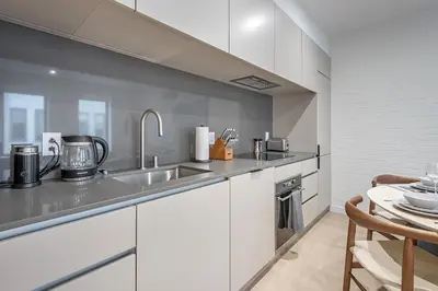 a kitchen with white cabinets and a sink and a table at Bright & Modern 2BR - Golden Square Mile in Montréal