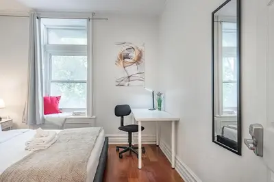 a bedroom with a bed and a desk and two windows at Elegant 3BR - High Ceilings & Vintage Charm in Montréal