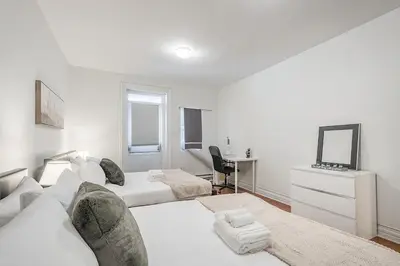 a white bedroom with two beds and a desk at Elegant 3BR - High Ceilings & Vintage Charm in Montréal
