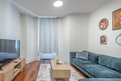 a living room with a green couch and a flat screen tv at Elegant 3BR - High Ceilings & Vintage Charm in Montréal