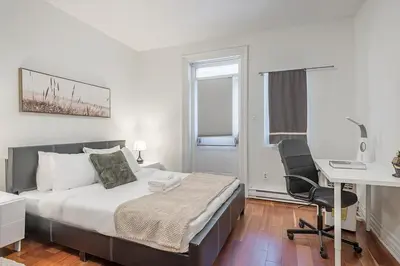 a bedroom with a bed and a desk and a computer at Elegant 3BR - High Ceilings & Vintage Charm in Montréal