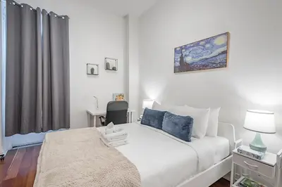 a bedroom with a white bed with blue pillows at Spacious 3BR Downtown - 2 Queen & Bunk & Sofa Bed in Montréal