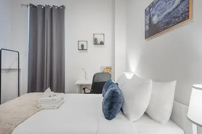 a bedroom with a white bed with a blue pillow on it at Spacious 3BR Downtown - 2 Queen & Bunk & Sofa Bed in Montréal