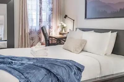 a bedroom with a white bed with a chair and a desk at Spacious 2BR Downtown - Vintage Charm Sleeps 10 in Montréal