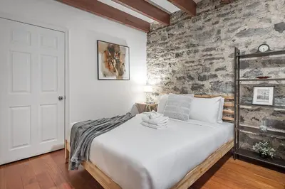 a bedroom with a white bed with a stone wall at Spacious 2BR Downtown - Vintage Charm Sleeps 10 in Montréal