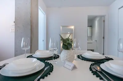 a dining room table with white plates and wine glasses at Charming 1BR Old Port - Sofa Bed - Balcony with City View in Montréal