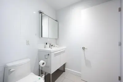 a white bathroom with a toilet and a sink at Charming 1BR Old Port - Sofa Bed - Balcony with City View in Montréal