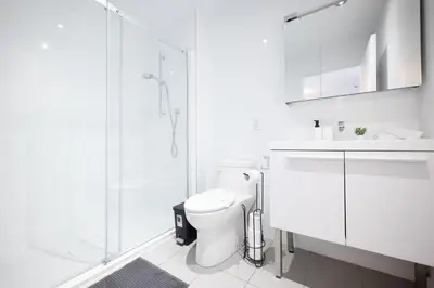 a white bathroom with a toilet and a glass shower at Charming 1BR Old Port - Sofa Bed - Balcony with City View in Montréal