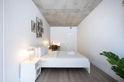 a white bedroom with a white bed and a desk at Spacious Apartment in Old Port Montreal in Montréal