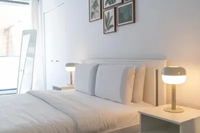 a bedroom with a bed with white sheets and a lamp at Spacious Apartment in Old Port Montreal in Montréal