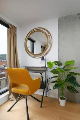 a yellow chair sitting next to a desk with a mirror at Chic Hideaway - Downtown Hotspot in Montréal