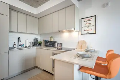 a kitchen with white cabinets and a table and chairs at Urban Hideout - Downtown Haven in Montréal