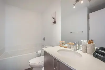 a white bathroom with a toilet and a sink at Corner 2BR Old Port - Free Indoor Parking in Montréal