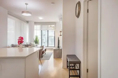 a kitchen and living room with white walls and a counter at Corner 2BR Old Port - Free Indoor Parking in Montréal