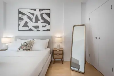 a bedroom with a white bed and a mirror at Corner 2BR Old Port - Free Indoor Parking in Montréal