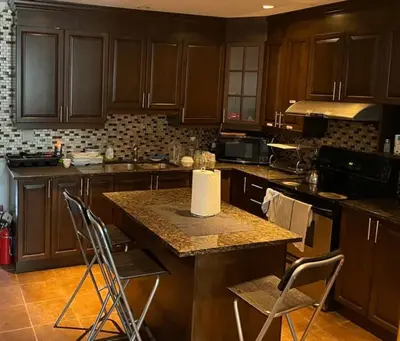 a kitchen with wooden cabinets and a counter with chairs at 2 Beds availabe and self service small breakfast in Montréal