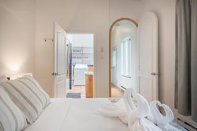 a white bedroom with a white bed with a mirror at Stylish Loft Retreat - Prime Location - Sleeps 8 in Montréal