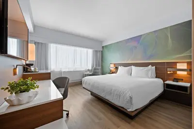 a hotel room with a bed and a desk at Armon Plaza Montreal Airport in Saint-Laurent