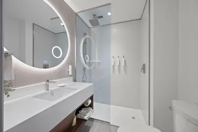 a white bathroom with a sink and a mirror at Armon Plaza Montreal Airport in Saint-Laurent