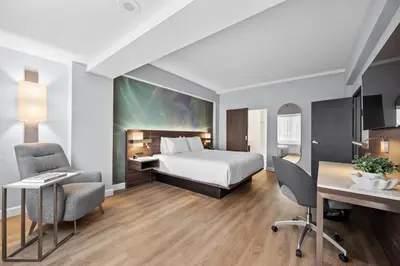 a hotel room with a bed and a desk and chairs at Armon Plaza Montreal Airport in Saint-Laurent