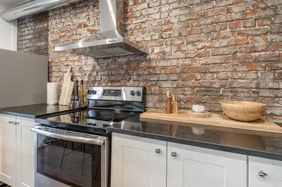 a kitchen with a stove and a brick wall at Modern 2BR - 2 Full Bathrooms - Trendy Griffintown in Montréal