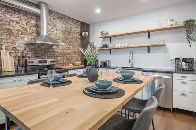 a kitchen with a wooden table with plates and glasses at Modern 2BR - 2 Full Bathrooms - Trendy Griffintown in Montréal