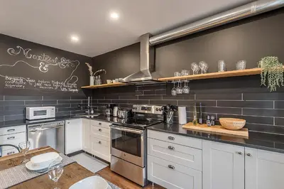 a kitchen with white cabinets and a black wall at Modern 2BR - 2 Full Bathrooms - Trendy Location in Montréal