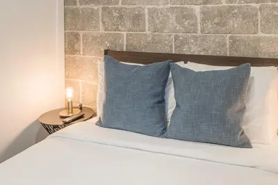 a bed with two blue pillows and a brick wall at Modern 2BR - 2 Full Bathrooms - Trendy Location in Montréal