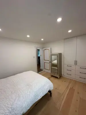 a white bedroom with a bed and a mirror at Maison prestige sur la rive in Laval