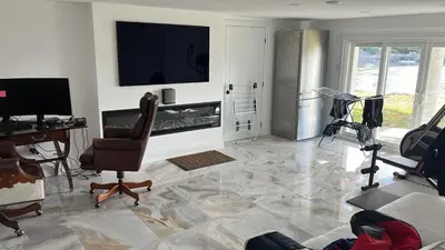 a living room with a tv and a chair and a desk at Maison prestige sur la rive in Laval