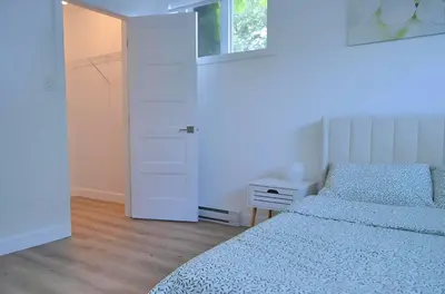 a white bedroom with two beds and a window at Urban Serenity NDG in Montréal