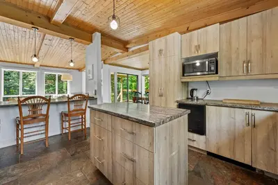 a kitchen with wooden cabinets and a counter top at Lake - Spa - Pool Table - Chalet Ookpik in Potton