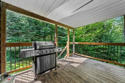 a screened in porch with a grill on a deck at Lake - Spa - Pool Table - Chalet Ookpik in Potton