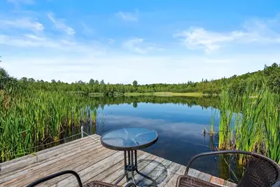 a table and chairs sitting on a dock next to a lake at Lake - Spa - Pool Table - Chalet Ookpik in Potton
