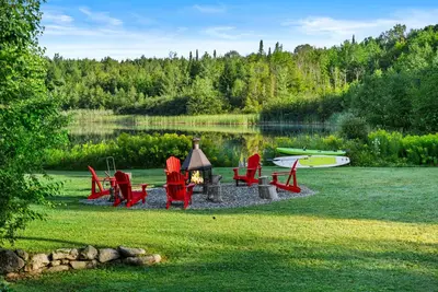 a group of red chairs and a fire in the grass at Lake - Spa - Pool Table - Chalet Ookpik in Potton