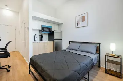 a bedroom with a bed and a small kitchen at Fabulous Studio with FREE Parking near Montreal Downtown in Montréal