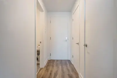 a hallway with white walls and a door and wooden floors at Skyline Suite - Modern 1 BR in Montréal