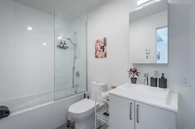 a white bathroom with a toilet and a shower at Cozy Corner - Modern 1BR in MTL in Montréal
