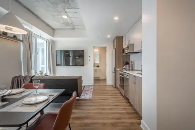a kitchen and a living room with a table and chairs at Cozy Corner - Modern 1BR in MTL in Montréal