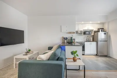a living room with a blue couch and a kitchen at The Nest - Comfy 1 bedroom in Prime Location in Montréal