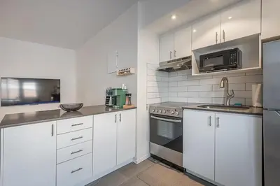 a kitchen with white cabinets and stainless steel appliances at The Nest - Comfy 1 bedroom in Prime Location in Montréal