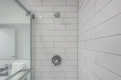 a white tiled shower with a silver drain at The Nest - Comfy 1 bedroom in Prime Location in Montréal
