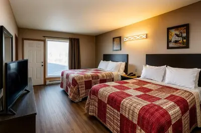 a hotel room with two beds and a flat screen tv at Motel St-Eustache in Saint-Eustache