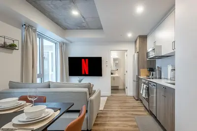 a kitchen and a living room with a n on the wall at Cute Gem in Downtown Montreal in Montréal