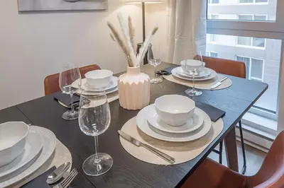 a dining room table with plates and wine glasses at Cute Gem in Downtown Montreal in Montréal